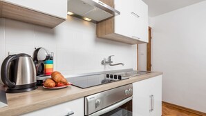 Een moderne keuken met een roestvrijstalen waterkoker, een broodrooster, een bord met croissants, een inbouwoven en een spoelbak.