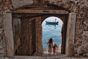A stone archway leading to a body of water with a boat in the distance. - Sorgenfrei 2-bedroom apartment in Rovinj Old Town (Rovinj)