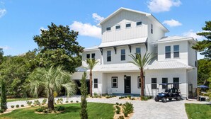 Une maison à deux étages avec une allée, des palmiers et un véhicule de golf.