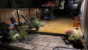 A patio with a wooden deck, potted plants, and outdoor furniture. - Great location! Fully fenced in yard and expansive deck. Come and relax! (Oak Island)