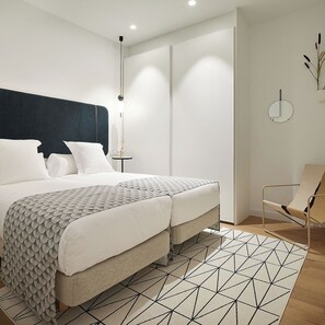 A modern bedroom with a bed, bedside table, and a chair. - La Belle Ville by FeelFree Rentals (San Sebastián)