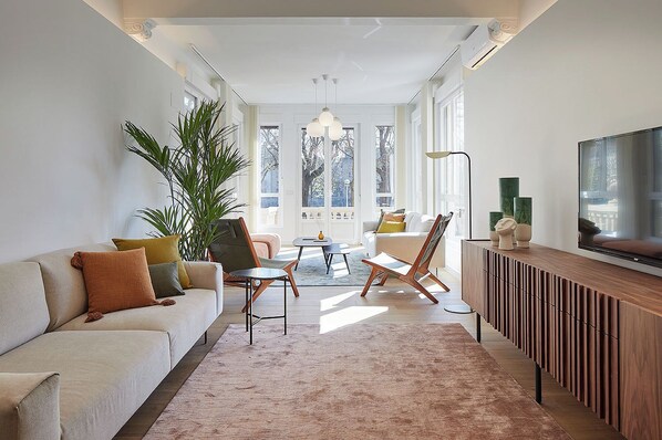A modern living room with a sofa, chairs, a coffee table, and a TV. - La Belle Ville by FeelFree Rentals (San Sebastián)
