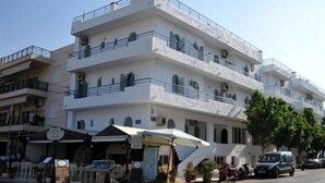 A multi-story building with balconies, a ground-level cafe, and a parked car. - Maria Apartments (Hersonissos)
