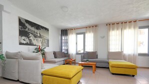 A modern living room with a sofa, ottoman, and a coffee table. - Maria Apartments (Hersonissos)
