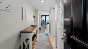 A hallway with a wooden bench, a framed picture, and a door with a security lock. - ~ Beach Bliss Escape ~ Oceanfront Condo! (Myrtle Beach)