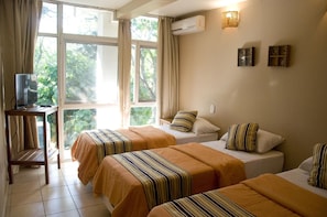Une chambre d’hôtel avec deux lits, une télévision et une fenêtre avec des rideaux.