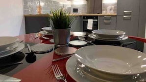 Et moderne køkken med lysegrå skabe, et rustfrit stål emfang og en central ø med en potteplante.