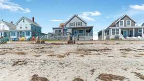 Una propiedad frente a la playa con varias casas, una playa de arena y una escalera de madera que lleva a una terraza.