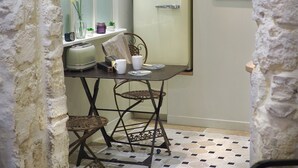 Una cucina compatta con un frigorifero vintage, un forno a microonde e un piccolo angolo ristoro con tavolo e sedie.