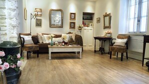 Un accogliente soggiorno con pavimento in legno, un divano bianco, un tavolino da caffè e un vaso decorativo con fiori.