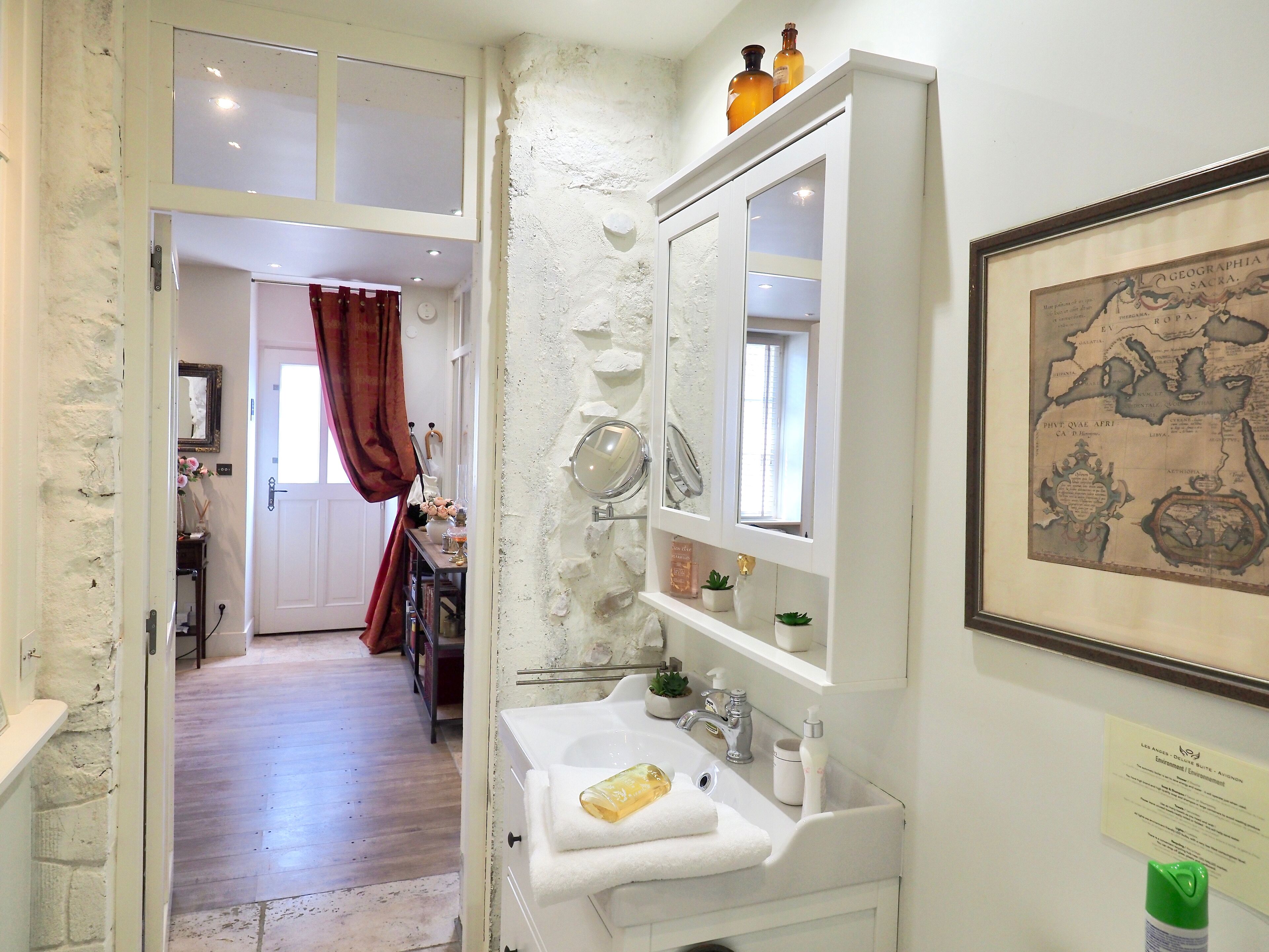 Un baño con un lavabo blanco, un espejo y un mapa enmarcado en la pared.