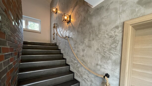 A staircase with a rope barrier, a wooden door, and two wall-mounted lights.