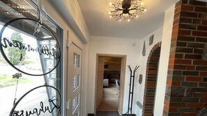A hallway with a glass door, a coat rack, and a brick wall.