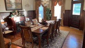 A dining room with a wooden table, chairs, a chandelier, and a fireplace.