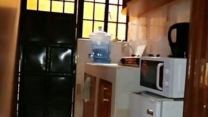 Keittiössä on jääkaappi, mikroaaltouuni ja vesiautomaatti.
