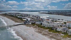Luftaufnahme einer Küstenstadt mit einer Pier, Strand und Wohnhäusern.