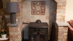A brick fireplace with a decorative tile design, a wooden mantel, and a 'Bless this House' sign above it. - Foot of the Mournes - Cottage - Sleeps 4 - Parking (Newry)