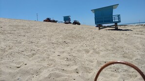 A sandy beach with lifeguard towers and a tractor.