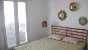 A bedroom with a wooden bed, a sliding glass door to a balcony, and two wall-mounted mirrors.