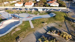 An aerial view of a skate park with various ramps and a parking area.