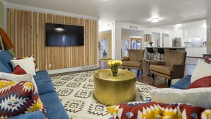 Un salon moderne avec un canapé bleu, un tapis à motifs et une table basse ronde ornée de fleurs jaunes.