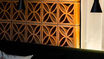 A room with a geometric patterned wall, a round table with a candle, and two black pendant lights.