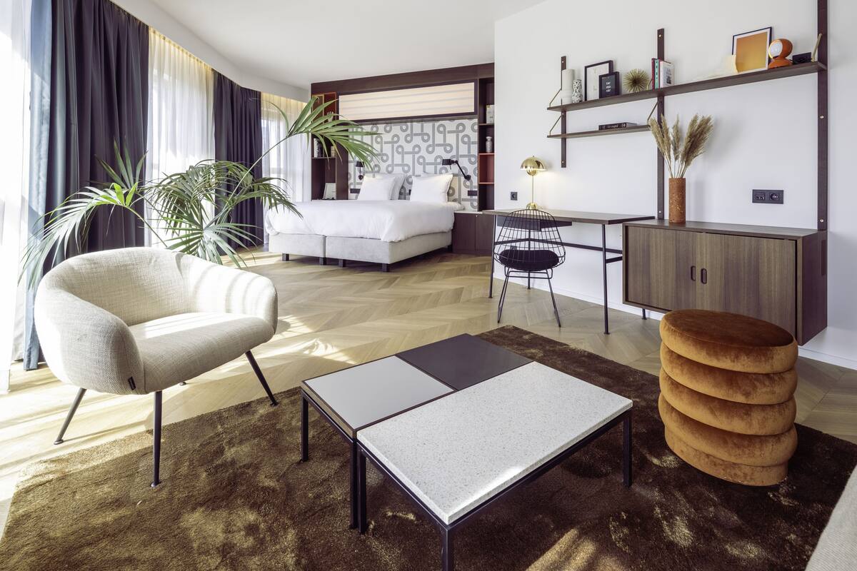 En moderne stue med sofa, lænestol, sofabord og et spiseområde med bord og stole.