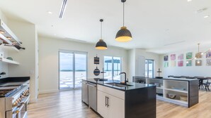 A modern kitchen with a large island, stainless steel appliances, and pendant lighting.