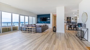 A spacious living area with a large window overlooking the sea, a modern kitchen, and a dining area with a view.