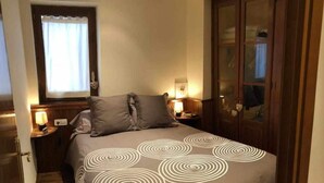A bedroom with a bed, two bedside tables, a window with curtains, and a wooden wardrobe. - Bellver Center (Bellver de Cerdaña)