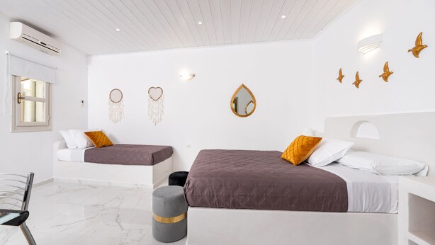 A modern bedroom with two beds, a vanity, and decorative wall art. - GK in Santorini Home ART (Santorini)