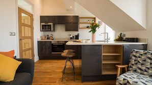 Una cocina moderna con armarios oscuros, una isla central y un comedor con una silla estampada.