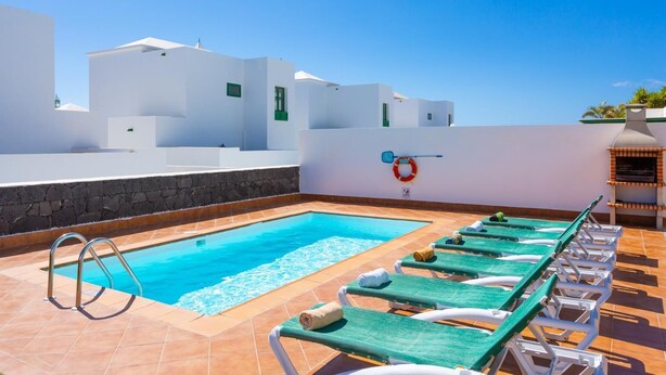 Un espace piscine aménagé sur le toit, avec une piscine à l’eau d’un bleu limpide, des chaises longues et un barbecue.