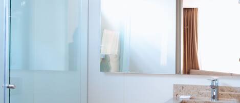 A modern bathroom with a glass shower enclosure, a white toilet, and a vanity with a mirror.