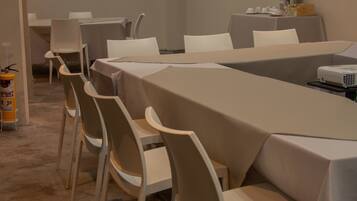 A conference room with tables and chairs, a projector, and a fire extinguisher.
