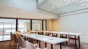 Een vergaderruimte met een lange tafel, stoelen en een modern plafondontwerp.