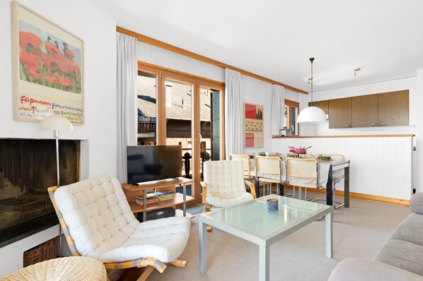A modern living room with a fireplace, a television, and a dining area with a table and chairs.