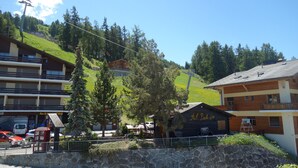 A hotel with multiple floors, a ski lift in the background, and a stone wall in the foreground.