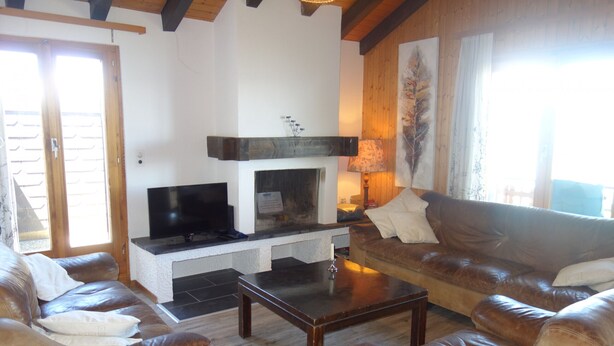 A living room with a fireplace, leather sofas, a coffee table, and a television.