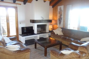 Ein Wohnzimmer mit Kamin, Ledersofas, einem Couchtisch und einem Fernseher.