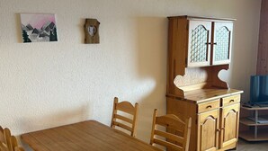 Un comedor con una mesa y sillas de madera, un aparador con puertas de cristal y un cuadro en la pared.