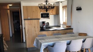 Een moderne keuken met houten kastjes, een centraal eiland en een eethoek met een tafel en stoelen.