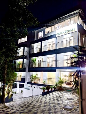 A multi-story hotel named "Green Royale" with balconies, potted plants, and a checkered pavement area. - Luxury 3-bed Serviced Apartment in Trivandrum (Thiruvananthapuram)