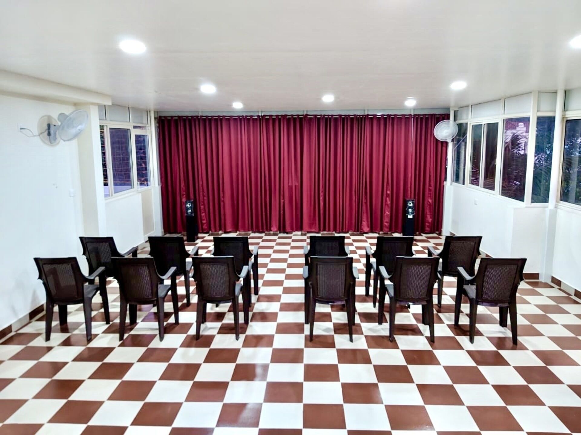 A conference room with a checkered floor, red curtains, and rows of chairs.