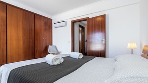 Ein Hotelzimmer mit einem Bett, einem Holzschrank, einem Schreibtisch mit Lampe und einer Klimaanlage.
