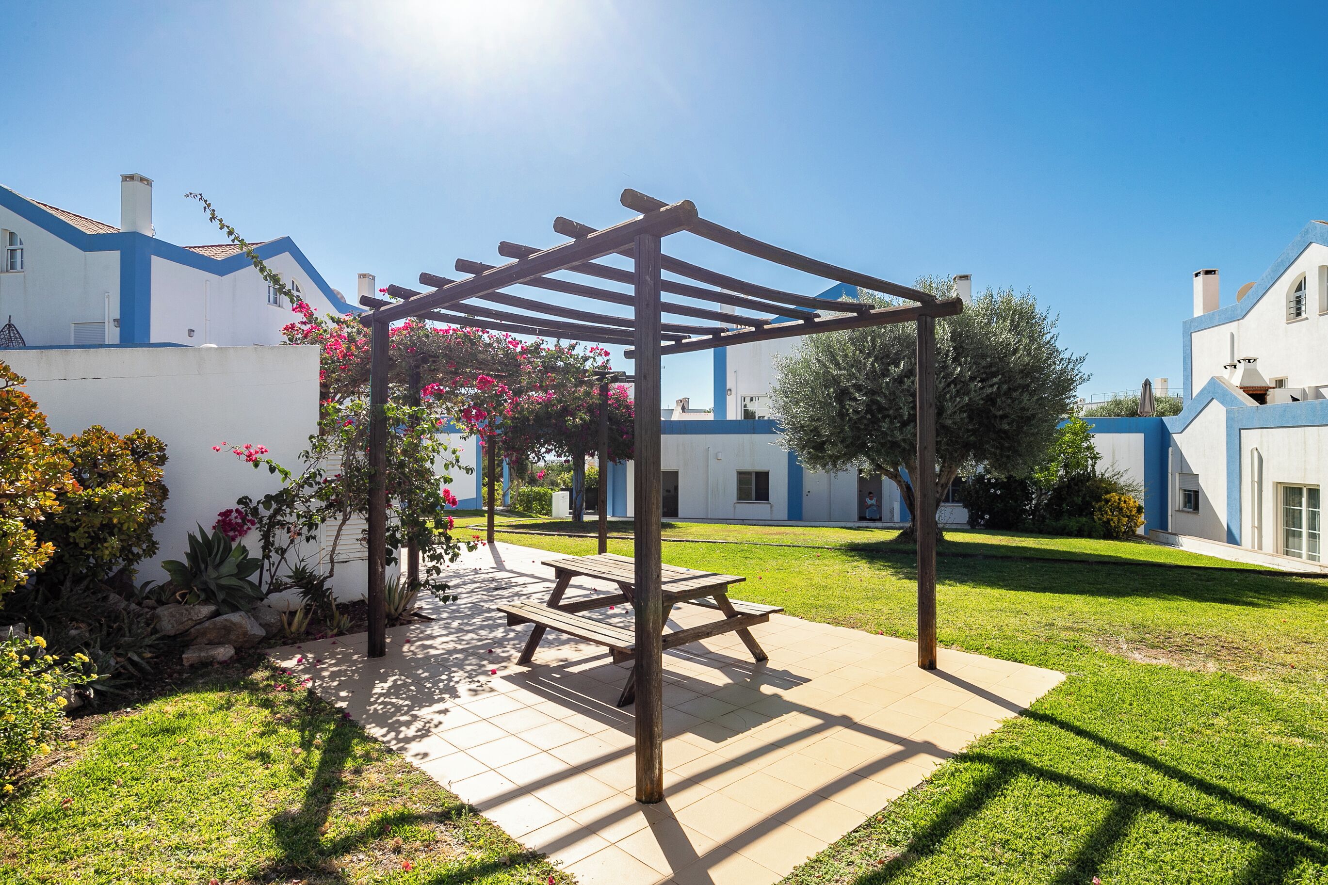 A garden with a wooden pergola, a picnic table, and a well-maintained lawn.