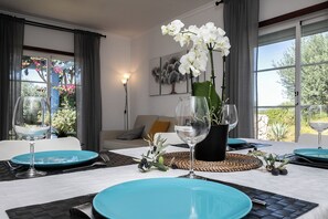 Un coin repas avec une table dressée pour deux personnes, agrémenté d’assiettes bleues et de verres à vin.