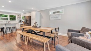A modern kitchen with white cabinets, a stainless steel refrigerator, and a wooden dining table with benches. - Helen, Georgia ★ Yonah Mtn, Hot Tub, Games + Grill (Helen)
