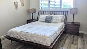 A bedroom with a wooden bed, two bedside tables, a window with blinds, and wall-mounted macramé decorations. - Beautiful, privately owned, Family Friendly, 3BR, Heated Pool, A+ Location! (Scottsdale)