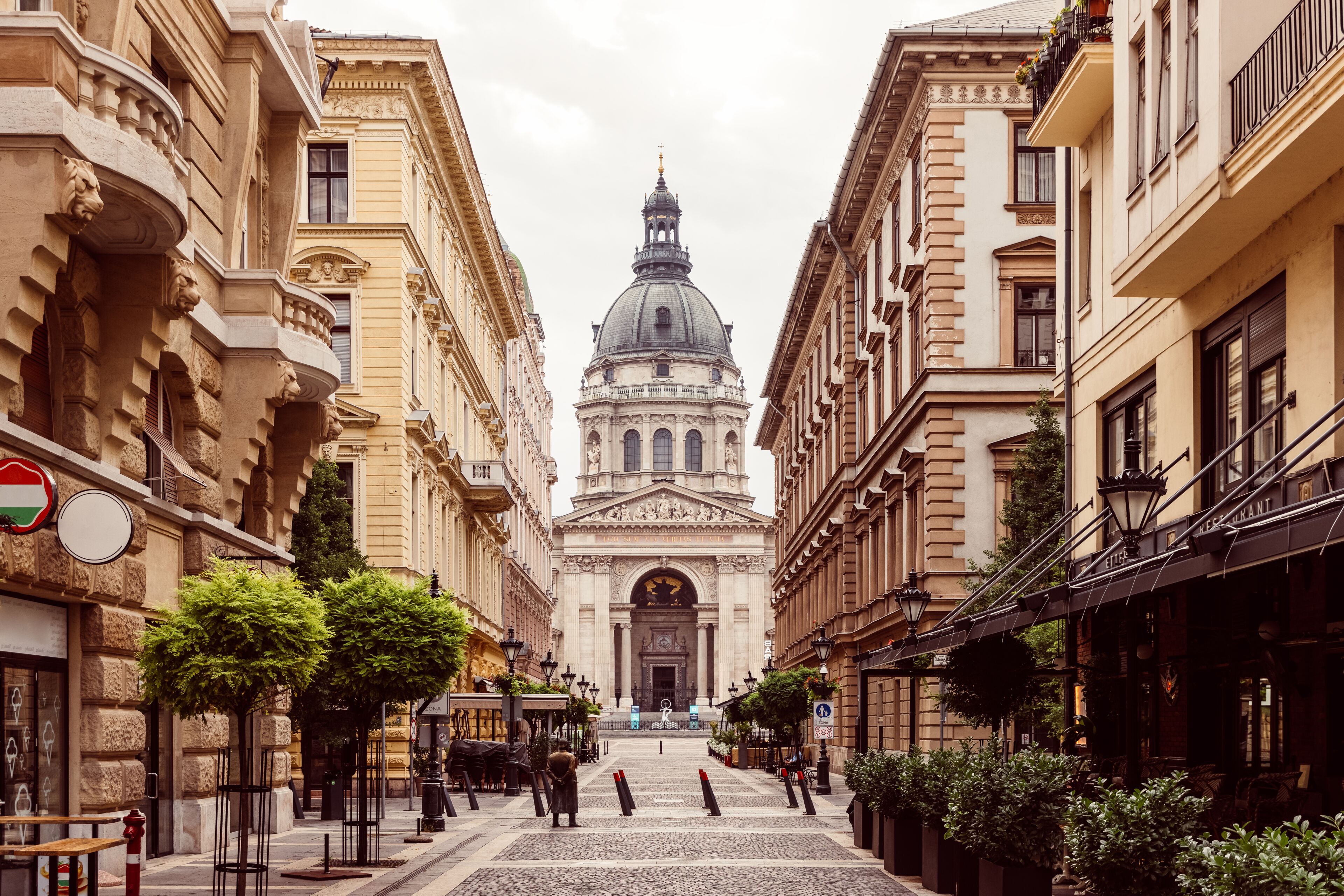 A street leading to a grand building with classical architecture, including a dome and columns.